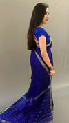 Woman wearing a blue saree with a plain background